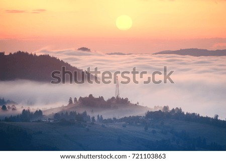 night in the mountains is fabulous and beautiful, the waves of the misty sea float in the valley against the backdrop of high peaks covered in forests. Below is a mountain village shining