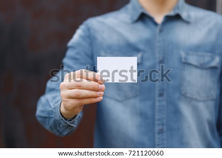 Man holding white business card on wall background