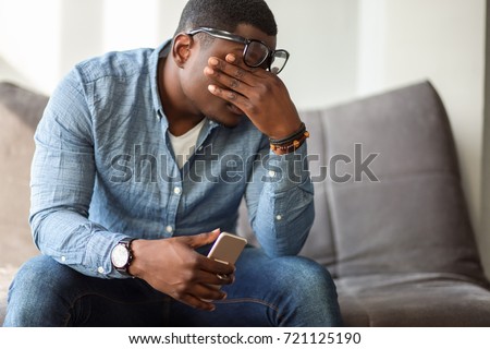 Feeling exhausted. Frustrated young black man massaging his nose and keeping eyes closed while sitting at his working place in office Royalty-Free Stock Photo #721125190