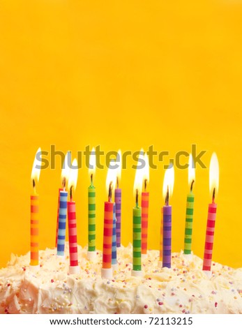 happy birthday cake shot on a yellow background with candles and lots of space