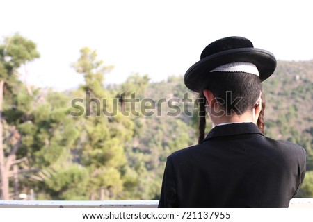 Orthodox Jew' dressed in a black coat and hat, looking at the landscape and the mountains