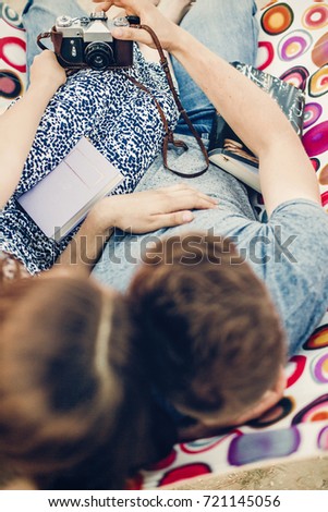Adorable hipster couple taking selfies on a hammock near the beach, beautiful girl and handsome man taking selfie with old film camera while on vacation with books