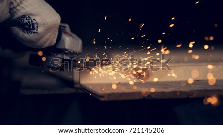 Man cut down the pin in wooden plank with lighting and cords using circular saw. Sparkles all over the place. Man at handmade diy work