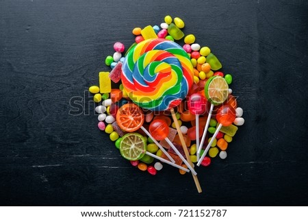 Colored candies, sweets and lollipops. On a black wooden background. Top view. Free space.