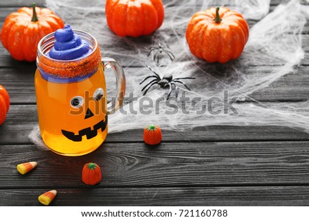 Halloween jelly in glass jar with candies on black wooden table