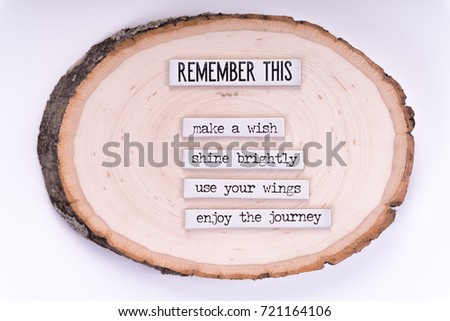 The words "Remember this", "Make a wish", "Shine brightly", "Use your wings" and "enjoy the journey" written on white strips, on top of a tree stump. Isolated in white backdrop.