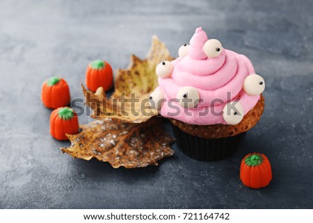 Halloween cupcake with candies on grey wooden background