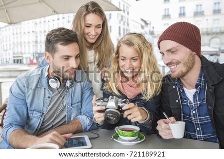 group of friends in coffee shop looking picture at vintage camera