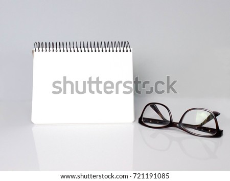 Front view of notebook and glasses on light grey background