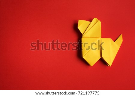 Yellow folded origami dog on red paper background. Horizontal holiday postcard, poster, banner template. Empty space for copy, text, lettering.