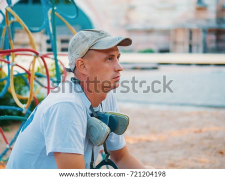 Young man portrait. Graffiti artist with protective mask sitting and looking to his picture.