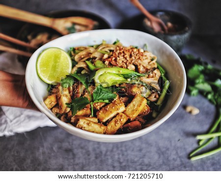  Hand hold bowl Udon with Padthai sauce, Healthy Vegetarian/vegan menu; Padthai noodle with smoke tofu and mixed vegetable - chinese baby Bok Choy , garlic chive, shallot and crushed peanut topping.  Royalty-Free Stock Photo #721205710