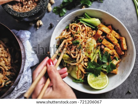  Udon with Padthai sauce, Healthy Vegetarian/vegan menu; Padthai noodle with smoke tofu and mixed vegetable - chinese baby Bok Choy , garlic chive, shallot and crushed peanut topping. chopstick hold. Royalty-Free Stock Photo #721206067