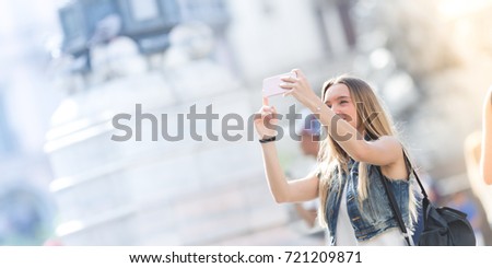 Pretty tourist teenager taking a photo with her mobile phone. Photo taken in Milan, Italy