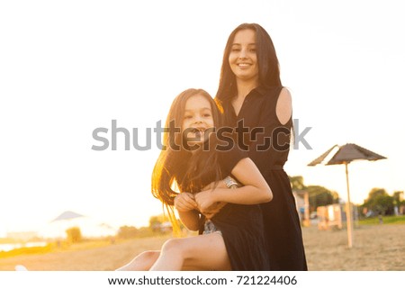 Young mother and daughter playing and walking on sandy beach