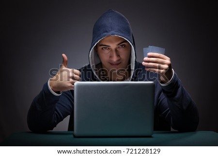 Young man wearing a hoodie sitting in front of a laptop computer