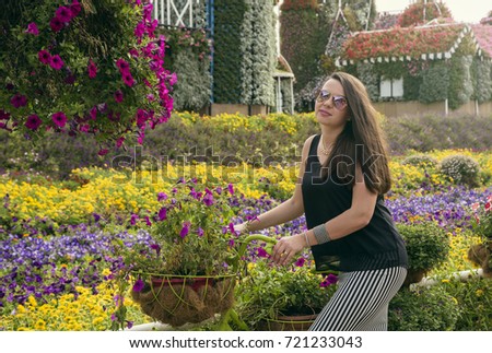 Girl riding bicycle with flower basket in miracle garden in dubai