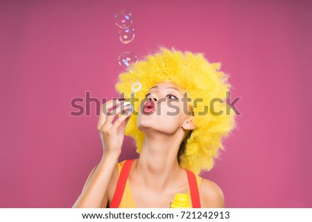 A funny girl in a wig blows bubbles. Clown