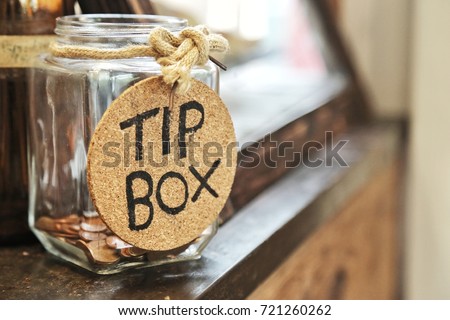Vintage retro glass jar with hemp rope tie tip box tag and few coins inside on wood counter Royalty-Free Stock Photo #721260262