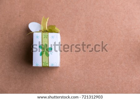 Small cute gift box with green ribbon on brown wooden board with blank space