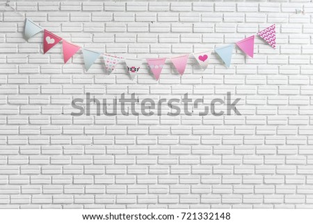 White brick wall decorated by colorful and pink cartoon flags for children or baby shower party event