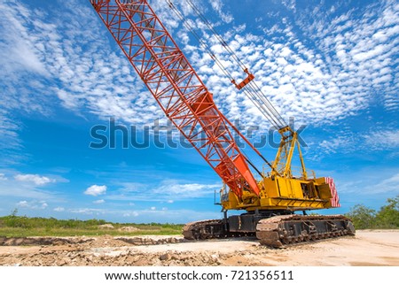 Yellow mobile crane  on operation in construction site with cloudy sky background
