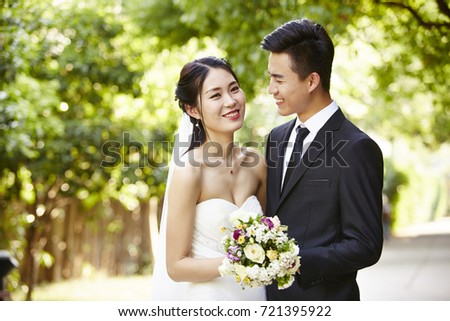 outdoor portrait of asian bride and groom, happy and smiling.