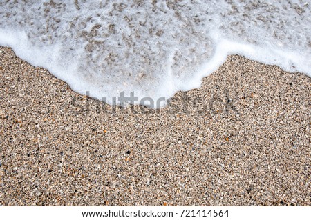 Soft wave of the tropical sea on the sandy beach. Natural summer background with copy space