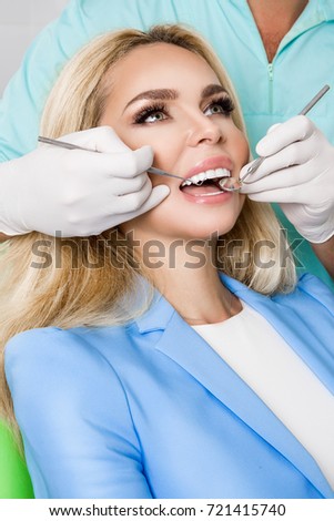 Porcelain veneers. Pretty female model with perfect smile. Young beautiful woman with beautiful white teeth sitting on a dental chair. Teeth whitening.