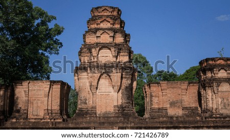 A sunny view of a minor Khmer temple within the Angkor Wat, Cambodia UNESCO site. This ancient landmark tower stands tall against the bright blue sky.