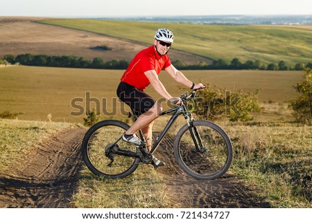 Bike adventure travel photo. Bike tourist rides on the country road. Sunset on background.
