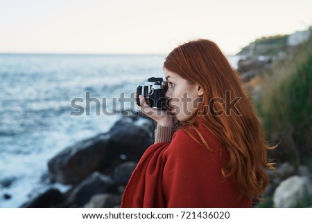 woman photographer in a warm blanket in nature takes pictures of the camera of the sea, sea air                               