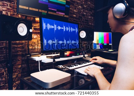 asian male hipster sound engineer working on computer in digital audio & video editing post production studio