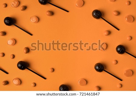 close-up view of sweet black and orange halloween lollipops on orange