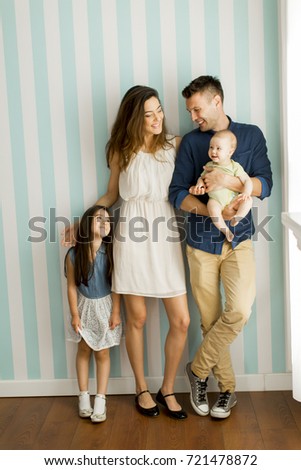 Young family with a baby and little girl standing  by the wall in the room