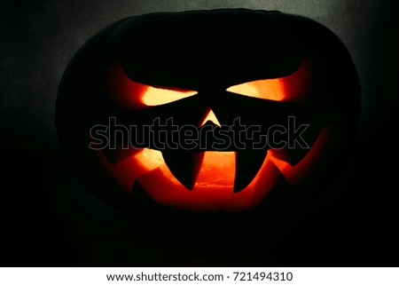 A very terrible Halloween pumpkin, with a terrible look and a smirk of a villain, in the dark