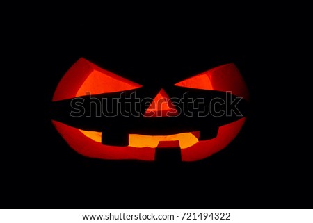 The concept of Halloween. The ghastly, ghastly pumpkin glows with a fiery yellow light. mystical jack lantern in the darkness, isolated on black