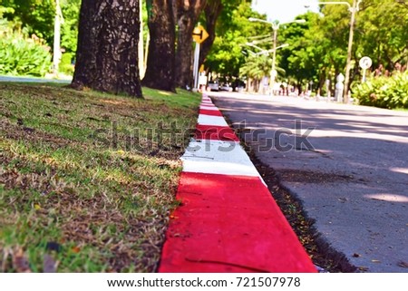 Red and white strip is no parking sign on footpath way, Red and white sign of concrete road. Perspective of red and white pathway sign. This image was blurred or selective focus. 