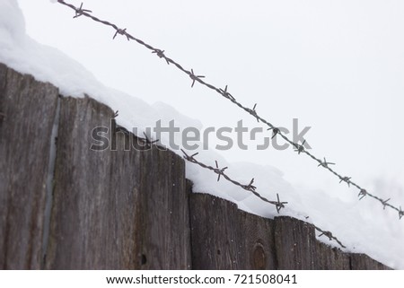 Barbed wire on dark fence. winter a lot of snow