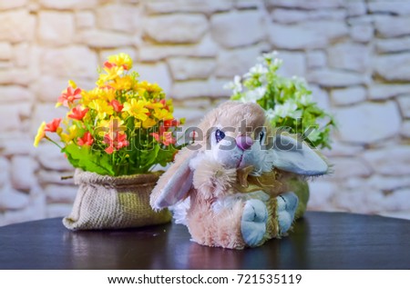 Rabbit dolls are on the table with flowers.