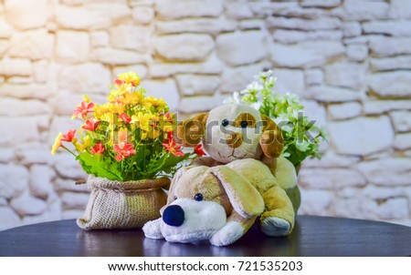 Dogs dolls are on the table with flowers.