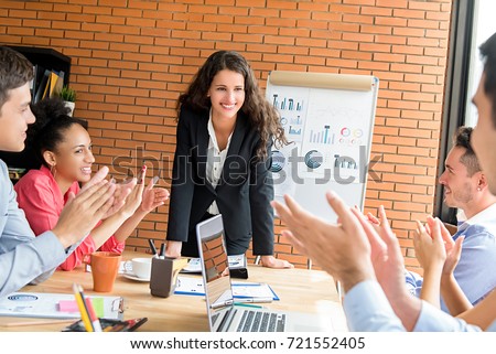 Colleagues giving the applause to beautiful successful young businesswoman leader in team meeting Royalty-Free Stock Photo #721552405