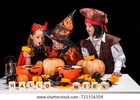 kids in halloween costumes of devil, witch and pirate making jack o lanterns of pumpkins, isolated on black