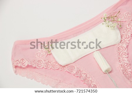 Hygienic tampon and sanitary napkin for every day with pink and white panties with green flowers on a white background