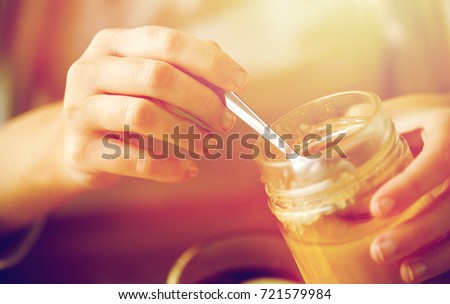 health, traditional medicine and ethnoscience concept - close up of woman hands with honey jar and spoon Royalty-Free Stock Photo #721579984