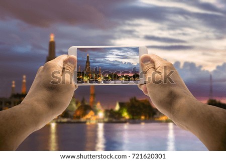 View of man's hands making photo on mobile phone camera of Wat Arun (Temple of Dawn) with Chao Phraya river,bangkok thailand