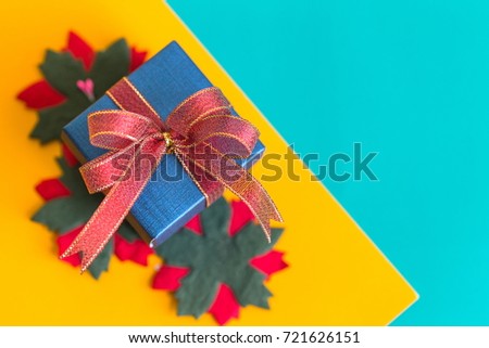 Beautiful red and green flowers and blue gift box on two tone background for celebration event