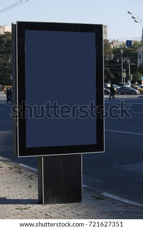 An empty street ad post with some blurred urban background