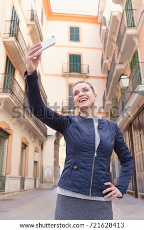 Portrait of beautiful young tourist woman visiting destination city holiday, pointing smart phone camera, taking selfies pictures, smiling networking outdoors. Travel technology recreation lifestyle.