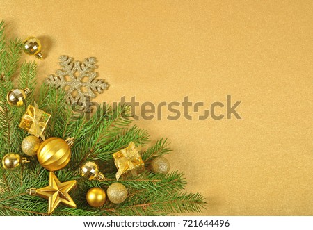 Golden Christmas decorations on a spruce branch on a golden background